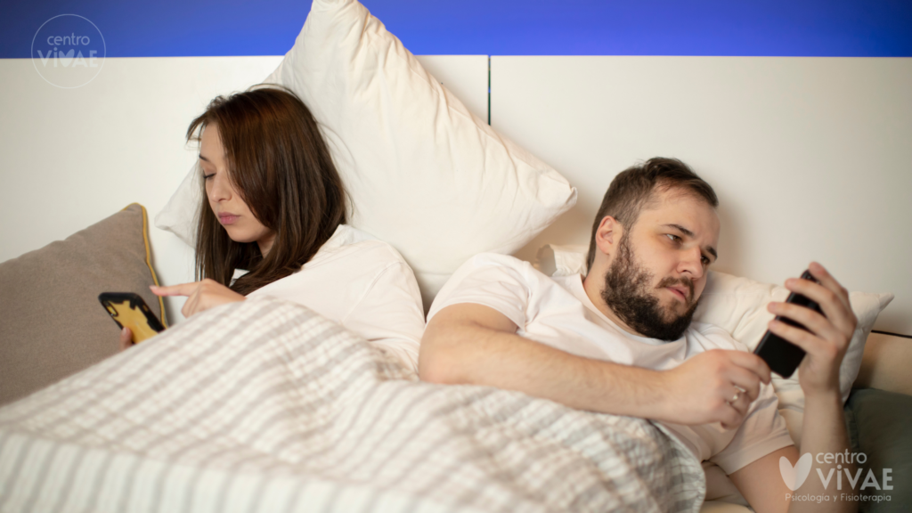 Pareja discutiendo en el sofá debido a la desconexión y los problemas de pareja por el móvil.